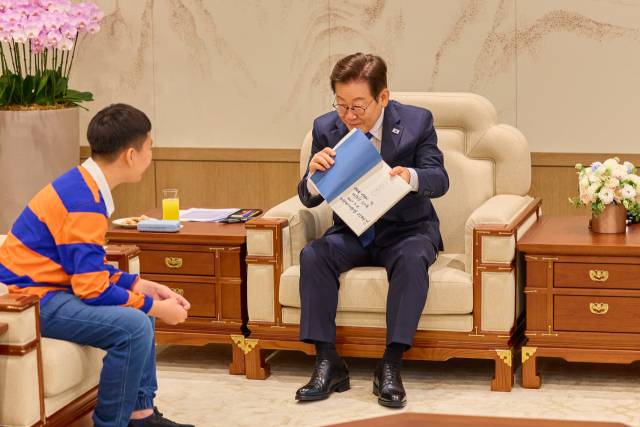 이재명 대통령이 4일 서울 용산 대통령실 청사에서 열린 어린이 초청 행사에 참석한 어린이에게 책을 선물하고 있다. 연합뉴스