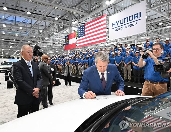 USA HYUNDAI OPENS NEW EV FACTORY IN THE US 브라이언 켐프(가운데) 조지아주 주지사가 현대차그룹의 조지아주 전기차 공장 개소식에서 정의선(왼쪽) 현대차그룹 회장이 보는 가운데 차량에 서명을 하고 있다. [EPA=연합뉴스 자료사진. 보도용으로만 사용 가능. 재판매 금지.]