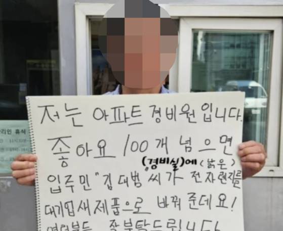 '좋아요 100개'를 달성하면 경비실 전자레인지를 바꿔주기로 했다는 내용의 스케치북을 들고 있는 경비원의 모습. 김대범 인스타그램