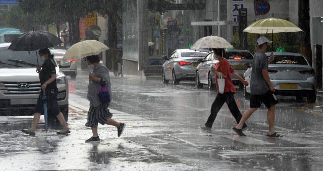 ▲ 강원 춘천 명동에서 시민들이 갑작스런 소나기에 우산을 쓰고 횡단보도를 건너고 있다. [강원도민일보 자료사진]