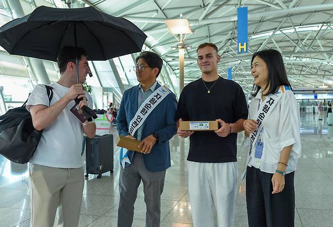 인천국제공항공사 직원들이 5일 제1여객터미널 3층 출국장에서 외국인 여객에게 페트병을 재활용해 만든 업사이클링 우산을 나눠주고 있다. 인천공항공사 제공