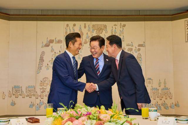이재명 대통령이 8일 서울 용산 대통령실에서 열린 여야 지도부 오찬 회동에서 정청래 더불어민주당 대표, 장동혁 국민의힘 대표가 악수하는 것을 보고 미소를 짓고 있다. 대통령실 제공