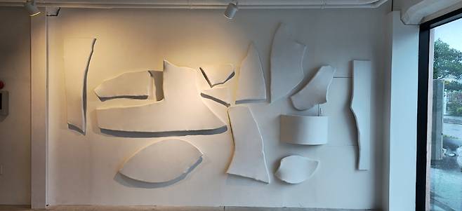 김상균 작가의 설치. 부서진 파편이 벽면을 따라 배치되고 빛을 머금는다. 단절과 연결, 파괴와 생성이 교차하는 장면이 덤지는 건 ‘회화의 확장’이라는 질문이다.