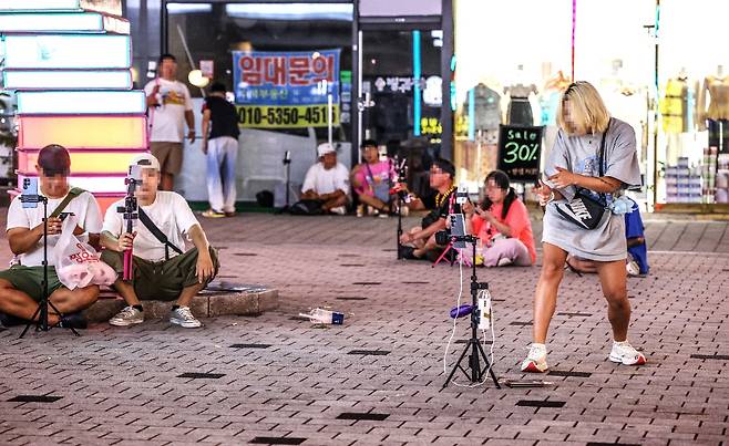지난 8일 밤 부천역 인근 상가 앞 광장 길바닥에서 유튜버·스트리머·BJ 등으로 불리는 이들이 휴대폰 카메라를 세워둔 채 춤추고 노래하며 실시간 방송을 진행하고 있다. 이들은 얌전한 축에 속한다. /주민욱 영상미디어 기자