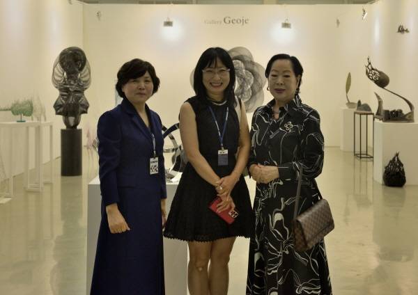 정홍연 갤러리거제 대표(왼쪽)와 미술 관계자들이 '제12회 경남국제아트페어' 작품을 배경으로 단체 기념촬영을 하고 있다.