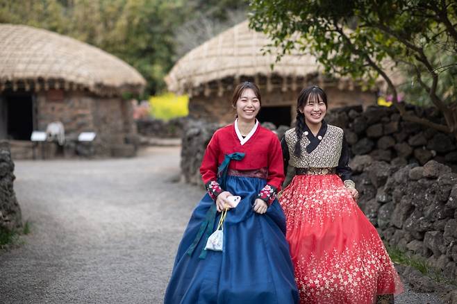 제주 민속 마을을 배경으로 한복을 입고 즐거운 시간을 보내는 글로벌 청년 인플루언서들. 일본·대만·베트남 청년들로 구성된 글로벌 서포터즈 ‘JJ프렌즈’가 제주의 로컬 문화를 직접 체험하며 SNS 콘텐츠로 전파하고 있다. (제주관광공사 제공)