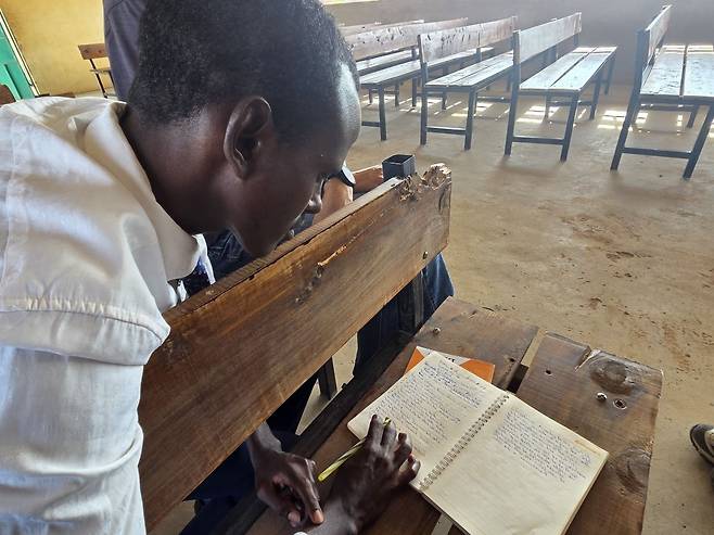 쿠레와 심데니아가 말리왁교회에 있는 장의자에 앉아 평소 작성한 설교 노트를 보여주고 있다.