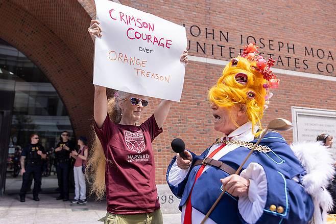 도널드 트럼프 미국 대통령으로 분장한 한 사람이 지난 7월 21일(현지시간) 매사추세츠주 보스턴의 존 조지프 모클리 연방 법원 밖에서 시위대와 얘기를 나누고 있다. 이날 하버드대학교 측 변호인단은 연방 법정에서 연방 정부가 20억 달러가 넘는 보조금과 계약을 동결한 것은 위법이며 철회돼야 한다고 주장했다.[게티이미지]