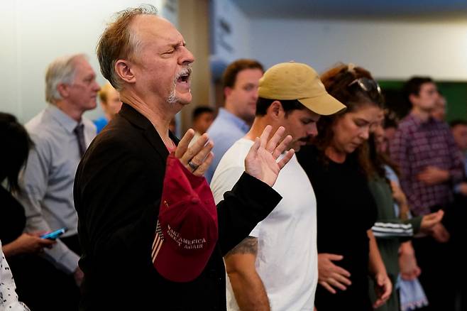 14일(현지시간) 미국 워싱턴 D.C. 케네디센터에서 열린 보수 성향 활동가 찰리 커크 추모 집회 후, 좌석이 가득 찬 뒤 로비에서 기도하고 있다. [로이터]