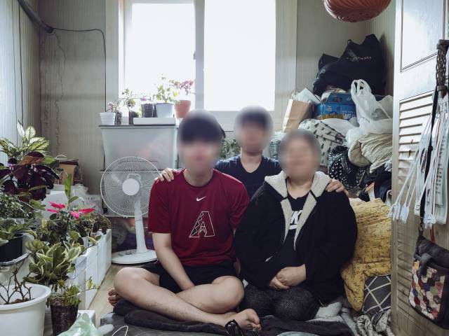 골수염과 골반 연골 소실 등으로 거동이 어려운 허은미(52·가명, 오른쪽) 씨가 곰팡이 핀 집에서 두 아들과 함께 생활하는 모습. 김지효 기자