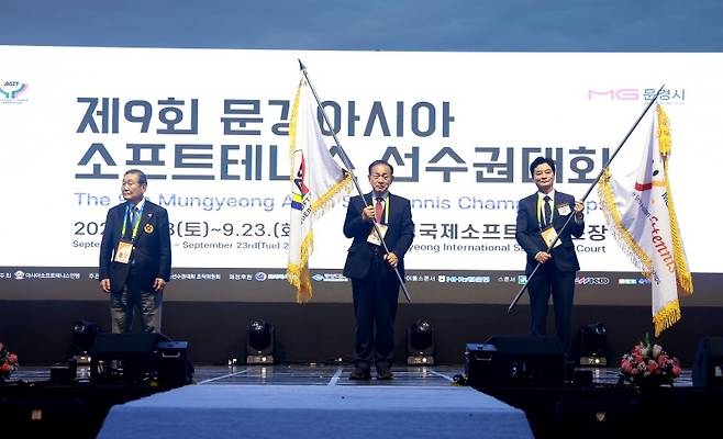 신현국 문경시장(가운데)과 정인선 대한소프트테니스협회 회장이 15일 제9회 문경아시아소프트테니스선수권 개회식에서 대회기를 흔들고 있다. 왼쪽은 안도 미츠지 아시아소프트테니스연맹 회장. 사진/대회조직위원회