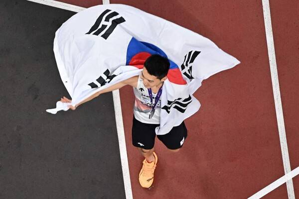 ‘스마일 점퍼’ 우상혁(용인시청)이 16일 일본 도쿄에서 열린 2025 세계육상선수권 높이뛰기 결선에서 은메달을 차지한 뒤 태극기를 들고 트랙을 돌고 있다. 도쿄/AFP 연합뉴스