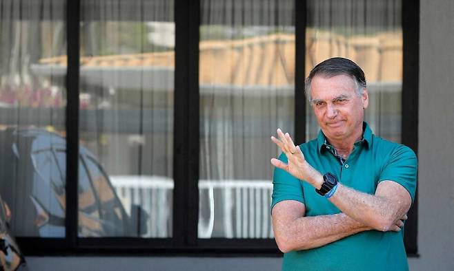 지난 11일 브라질 수도 브라질리아에 있는 자택에서 손을 흔들고 있는 자이르 보우소나루 브라질 전 대통령. 16일(현지시각) 가택 연금 중인 보우소나루 브라질 전 대통령은 건강 악화로 병원으로 긴급 이송됐다. AFP 연합뉴스