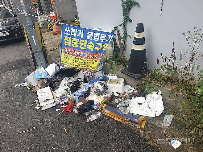 17일 광주 북구 용봉동의 한 주택가 골목 '불법투기 집중단속구역' 현수막 아래로 불법투기 쓰레기가 버려져 있다.