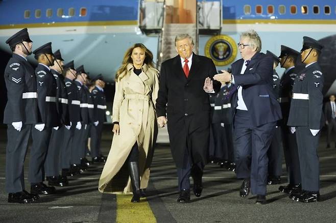 도널드 트럼프 미국 대통령과 멜라니아 여사가 16일(현지시간) 영국 런던 스탠스테드 공항에서 왕실 시종관인 후드 자작의 안내를 받으며 의장대 사이를 걷고 있다. AP연합뉴스