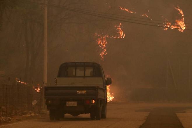 의성 산불 나흘째인 25일 오후 경북 안동시 길안면 백자리에 강풍이 불어 주변 산이 화염에 휩싸인 가운데 주민들이 대피 명령이 내려진 마을을 떠나고 있다. 2025.3.25 뉴스1