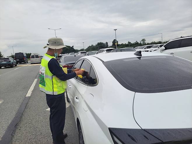 한국공항공사 청주지사 관계자가 청주국제공항 주차장 주변에 세워진 불법주차 차량에 이동안내 스티커를 붙이고 있다. 한국공항공사 청주지사 제공.