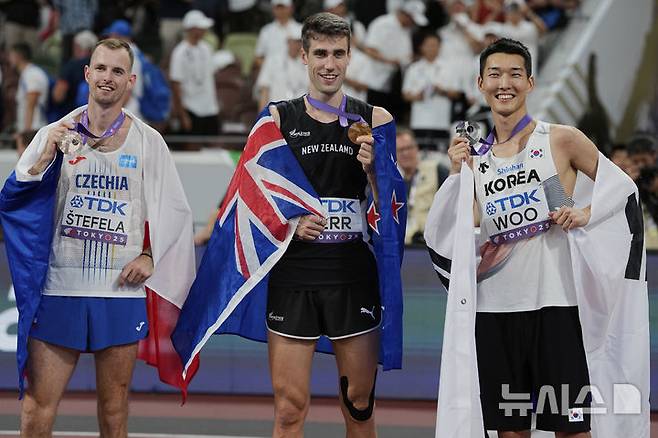 [도쿄=AP/뉴시스] 우상혁(오른쪽)이 16일 일본 도쿄 국립경기장에서 열린 2025 도쿄 세계육상선수권대회 남자 높이뛰기 결선에서 2ｍ34로 은메달을 획득한 뒤 금메달의 해미시 커(뉴질랜드, 가운데), 동메달의 얀 스테펠라(체코)와 포즈를 취하고 있다. 2025.09.16.