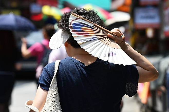 열대야와 폭염이 연일 이어지는 가운데 9일 서울 동작구 남성시장에서 한 시민이 부채로 햇빛을 가리고 있다. 2025.7.9 홍윤기 기자