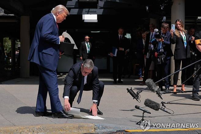 트럼프 대통령이 떨어뜨린 서류 줍는 스타머 총리 [AFP 연합뉴스 자료사진. 재판매 및 DB 금지]