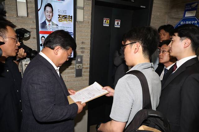 지난 18일 서울 여의도 국민의힘 중앙당사 현관 엘리베이터 앞에서 김건희 특검팀이 제시한 압수수색 영장을 국민의힘 쪽 변호사가 읽고 있다. 윤운식 선임기자 yws@hani.co.kr