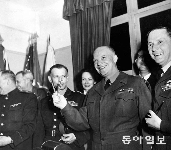 드와이트 아이젠하워 장군이 1945년 5월 7일 프랑스 랭스에서 독일의 무조건 항복 서명에 사용된 두 개의 펜으로 승리를 상징하는 V자를 만들고 있다. 전쟁 영웅이었던 아이젠하워는 1953년 대통령 취임 뒤 진보적 어젠다를 수용하며 강경 우파와 다른 길을 갔다. 동아일보DB