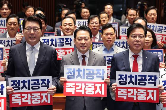 장동혁 대표(가운데)를 비롯한 국민의힘 의원들이 19일 국회 의원총회에서 더불어민주당의 정치 공작 중단을 촉구하는 구호를 외치고 있다. [뉴스1]