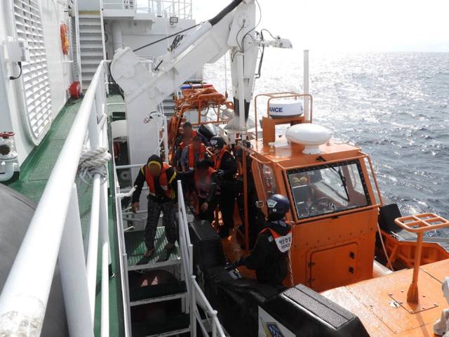 지난 19일 부산 송정 앞바다에 빠졌다가 인근 어선에 의해 구조된 어선 승선원들이 해경 경비정에 올라타고 있다. 연합뉴스