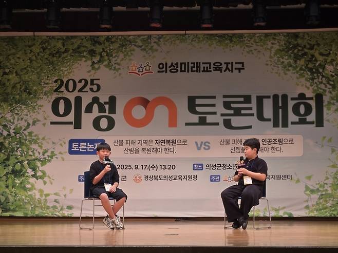 ▲ 17일 의성군청소년센터 대강당에서 열린 2025 의성ON토론대회에서 두 학생이 무대에 나란히 앉아 '산불 피해 지역의 산림 복원 방식'을 주제로 각자의 주장을 마이크를 통해 열띤 토론으로 펼치고 있다. 경상북도 의성교육지원청