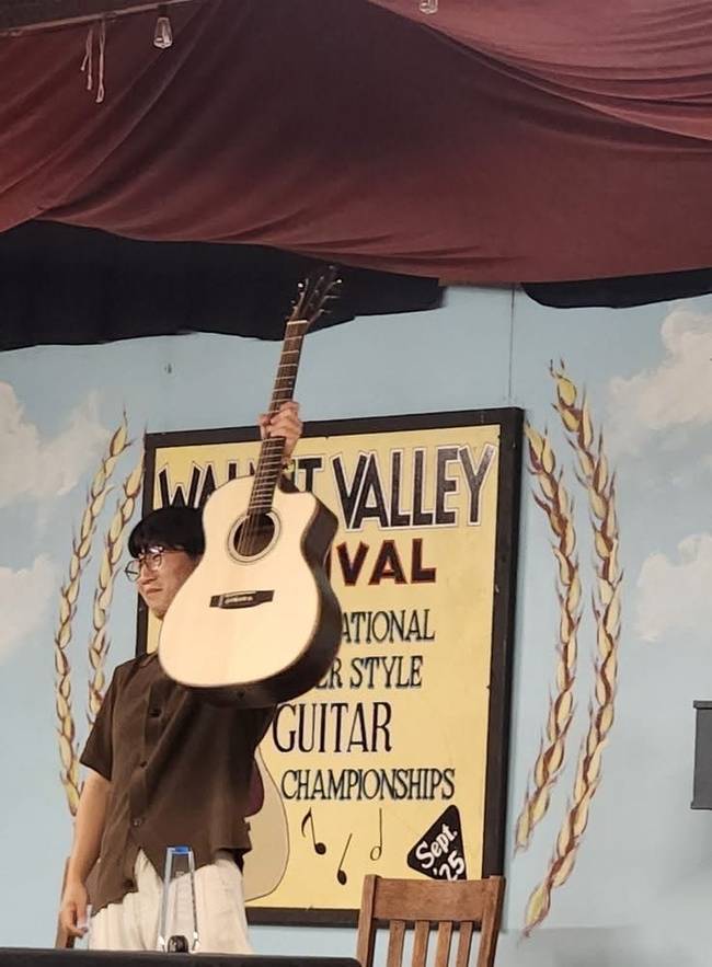 ▲ 김화종(31· 버클리음대 4년) 핑거 기타리스트가 지난 19일(미국 현지시간 18일) 미국 캔자스주 윈필드에서 개최된 '53회 월넛 밸리 페스티벌 2025 국제 핑거스타일 기타챔피언쉽 대회'에서 1위를 차지한 후 기타를 들어보이는 모습. 경북일보 독자 제공