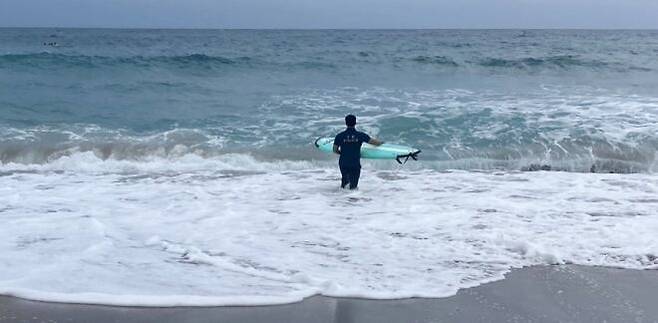 서핑보드를 타고 들어가 바다에 빠진 관광객을 구조한 제주 경찰./제주경찰청