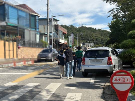 21일 대전 유성구 진잠동 방동저수지 윤슬거리 인근 주차장에 세워진 차량 사이로 보행자들이 지나고 있다. 최다인 기자