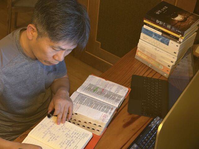 컴퓨터 앞에서 성경책을 읽으며 묵상글을 적고 있는 최 원장 옆 모습.
