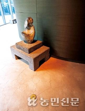 현무암을 활용한 돌천으로 마감된 검은 벽과 화산회토의 질감이 드러나는 바닥.