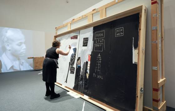 18일 오후 서울 동대문디자인플라자(DDP) 장 미셸 바스키아 특별전 전시장에서 ‘육체와 영혼’ 아랫 부분을 쿠리에(작품 호송인) 니키 슈미트가 검수하고 있다. 김성룡 기자