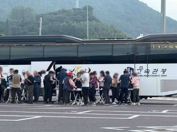 지난 21일 남해고속도로 순천방면 진영휴게소 주차장에서 남녀 무리들이 간이 테이블을 여러 대를 붙여 놓고 서서 음식을 먹고 있다. [보배드림 갈무리]