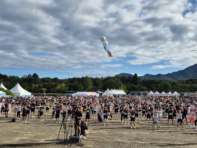 22일 열린 ‘2025 한돈런’ 달리기대회에서 참가자들이 무대 앞에 있는 치어리더가 보여주는 몸풀기 체조를 따라 하고 있다.