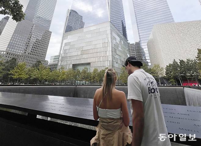 9·11테러 당시 붕괴된 세계무역센터 자리에 마련된 거대한 추모 폭포 앞에서 한 커플이 폭포 둘레에 새겨진 희생자들의 이름을 확인하고 있다. 뉴욕=임우선 특파원 imsun@donga.com