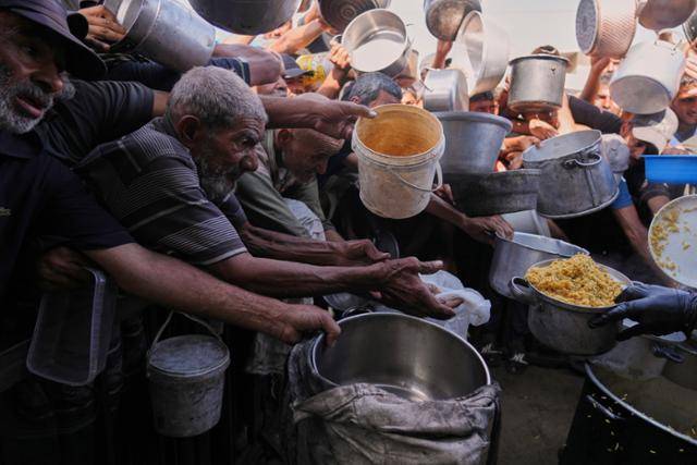 19일 가자지구 남부 칸유니스 공동 급식소에서 팔레스타인 주민들이 구호 음식을 받기 위해 몰려들고 있다. 칸유니스=AP뉴시스