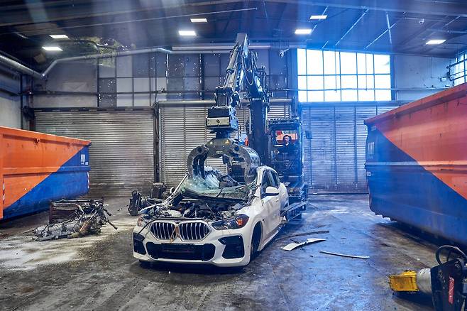 A giant excavator crushes a BMW sedan to extract wiring harnesses, which contain recyclable copper, at the company's Recycling and Dismantling Center on the outskirts of Munich. [BMW KOREA]