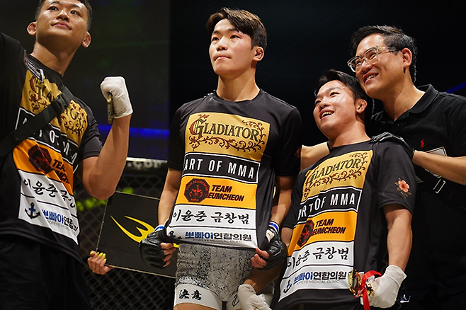 KMMA 페더급 타이틀 도전 예정자 김지경이 2025년 9월 일본 오사카 글래디에이터 032에서 종합격투기 프로 데뷔승 기념 촬영을 하고 있다. 오른쪽은 로드FC 플라이급 챔피언 이정현, KMMA 정용준 공동대표. 사진=대구반월당역 뽀빠이연합의원 제공