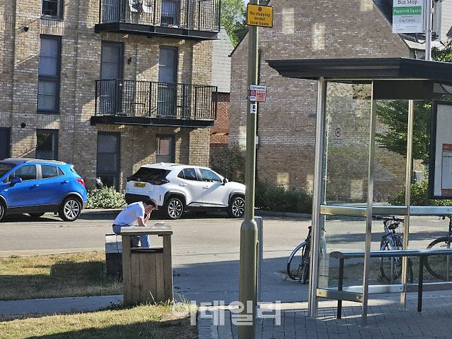 런던 교외에서 한 청년이 책을 보며 버스를 기다리고 있다. 영국 내에서 스마트폰을 통해 인터넷 사용률은 늘었지만, 일부 지역과 특정 장소에서는 인터넷 사용이 어려워 아직도 책을 읽는 인구가 많은 편이다. (사진=안치영 기자)