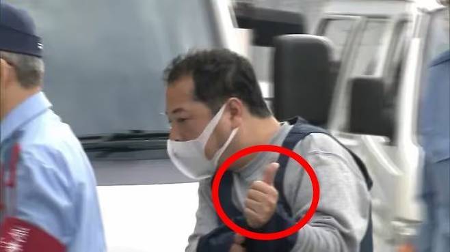 기소된 게스트하우스 사장 다케우치 도시하루(51)가 2022년 검찰 송치 당시 취재진 카메라를 향해 엄지를 치켜세운 모습. FNN