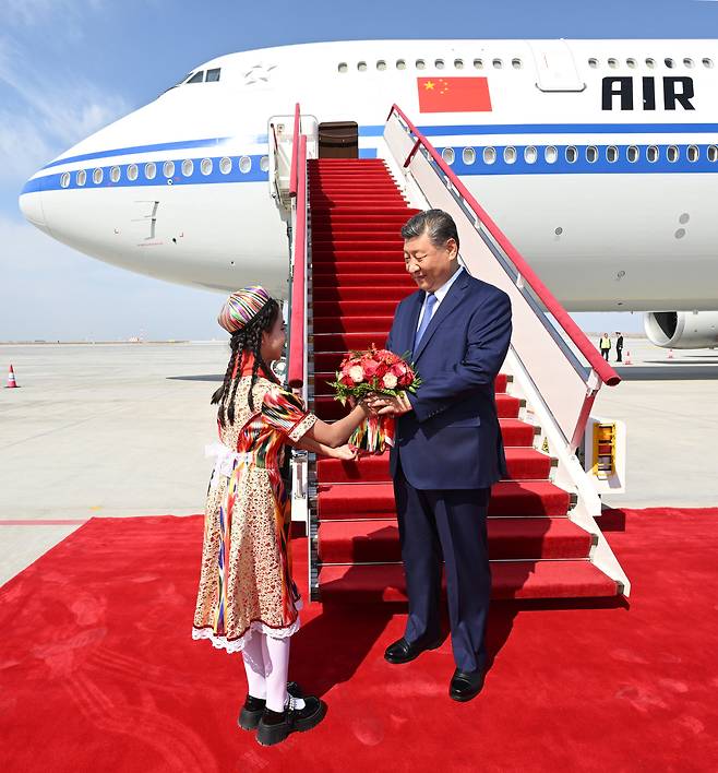 신장위구르자치구 설립 70주년 기념식을 위해 우루무치를 방문한 시진핑 중국 국가주석이 지난 23일 공항에서 위구르 전통복장을 한 소녀로부터 환영 꽃다발을 받고 있다./신화연합뉴스