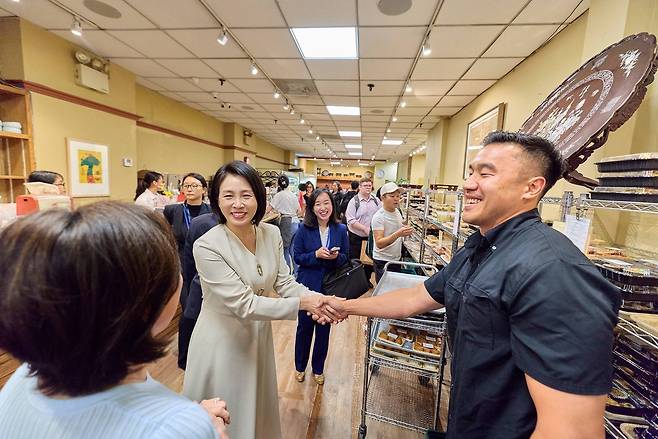 이재명 대통령과 함께 미국 뉴욕을 방문한 김혜경 여사가 23일(현지시간) 코리아타운의 한 반찬가게를 방문해 식당 관계자와 악수를 나누고 있다. [연합]