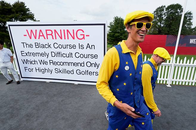 지난 24일 라이더컵을 앞두고 미국 뉴욕 파밍데일의 베스페이지 블랙 골프장에서 열린 연습 라운드를 관람하기 위해 팬들이 입장하고 있다. 뒤쪽에 이곳은 너무 어려운 코스이니 실력이 뛰어난 골퍼들만 도전하는 게 바람직하다는 취지로 쓰인 간판이 보인다. AP