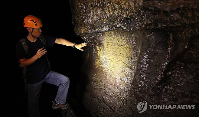 제주 용천동굴 안의 사람 흔적 (제주=연합뉴스) 박지호 기자 = 국가유산 방문의 해를 맞아 제주시 구좌읍 월정리 용천동굴이 25일 언론에 특별공개됐다. 
    기진석 제주도 세계유산본부 세계유산팀장이 동굴 내부 벽면의 그림 흔적에 대해 설명하고 있다. 2025.9.25 jihopark@yna.co.kr