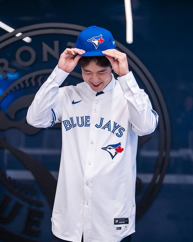 문서준이 25일(이하 한국시각) 캐나타 토론토 로저스센터에서 메이저리그 토론토 블루제이스와 입단계약을 체결한 뒤 유니폼을 입으며 환하게 웃고 있다. 사진제공=리코스포츠에이전시