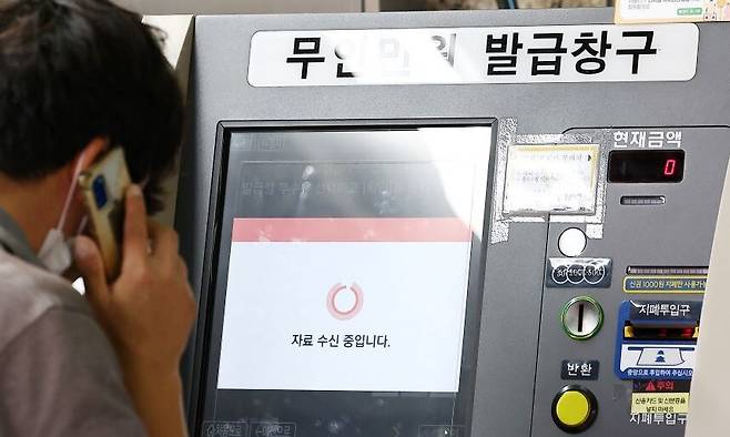 26일 국가정보자원관리원 대전 본원에 있는 전산실에서 발생한 화재로 정부 업무시스템 647개가 가동이 중단된 것으로 파악됐다. 27일 서울 시내 한 지하철역에 설치된 무인민원발급기에서 한 시민이 서류가 발급되지 않자 통화를 하고 있다. 연합뉴스