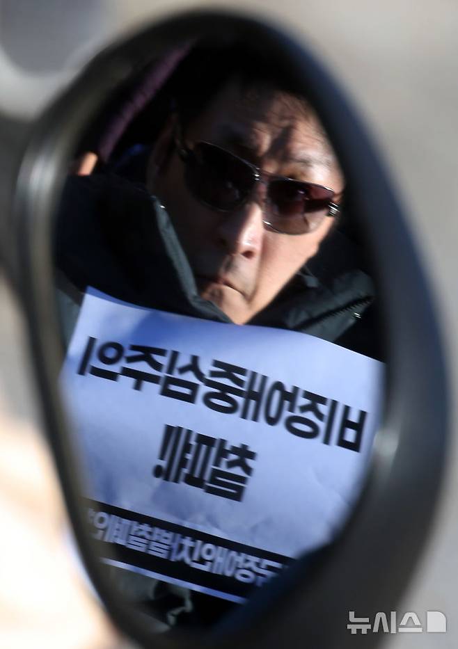 [서울=뉴시스] 조성봉 기자 = 3일 오후 서울 여의도 국회 본청 앞 계단에서 열린 '장애인 권리약탈 STOP 긴급 촉구 국회 기자회견'에서 '비장애인중심주의 철폐' 손피켓을 든 한 참가자의 모습이 전동휠체어 백미러에 비춰보이고 있다. 2024.12.03. suncho21@newsis.com